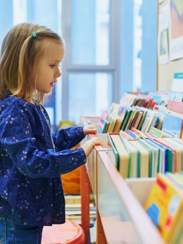 4 year old girl selecting a book in municipal library
