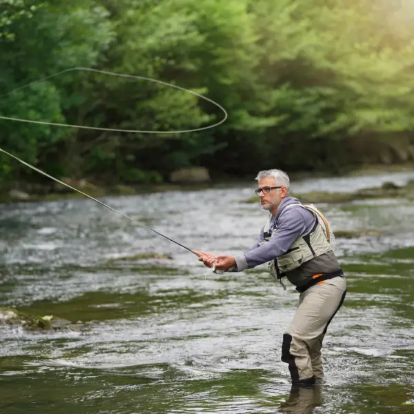 Pêcheur à la mouche dans une rivière en forêt