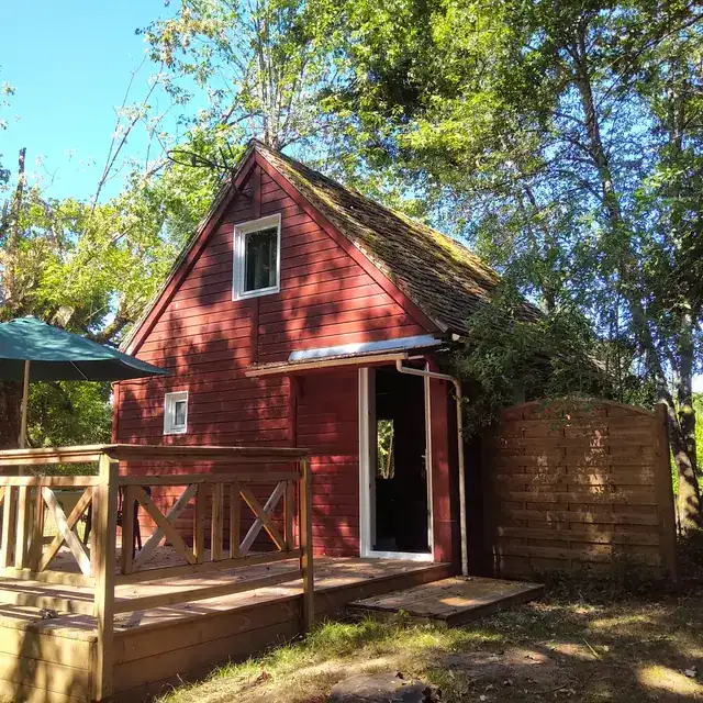 Petite cabane en bois rouge entourée d'arbres verts