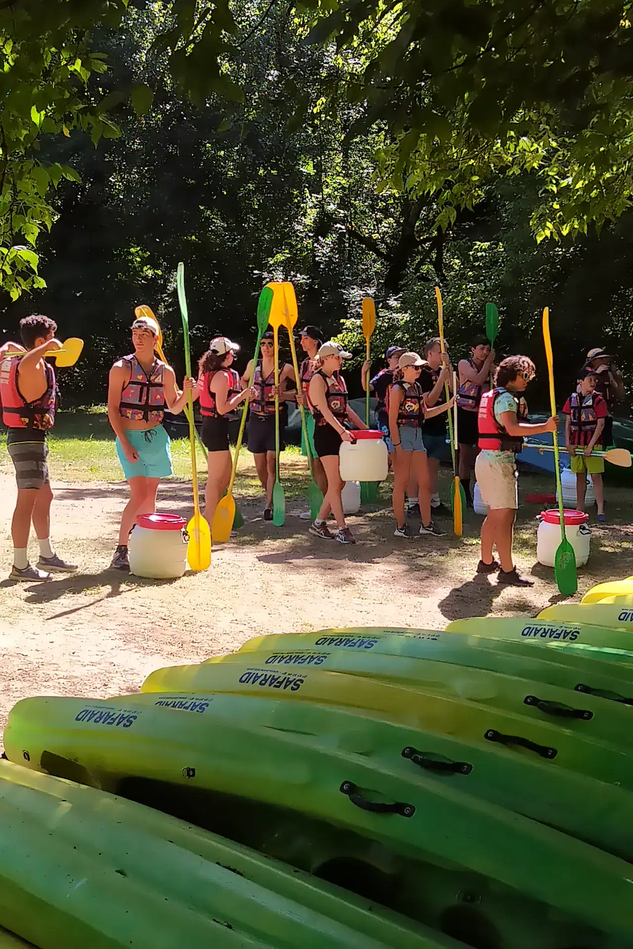 Groupe de jeunes en gilets de sauvetage tenant des pagaies