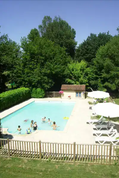 Piscine extérieure avec baigneurs en été entourée d'arbres