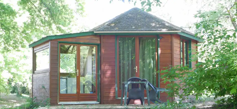 Chalet en bois avec terrasse entouré d'arbres verdoyants